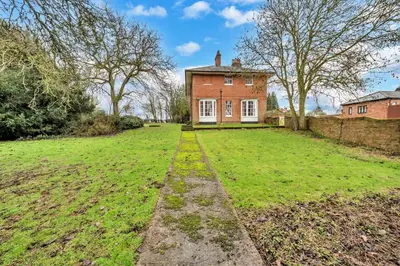 an empty field in front of a brick house at Finest Retreats - Clavering Hall in Saffron Walden