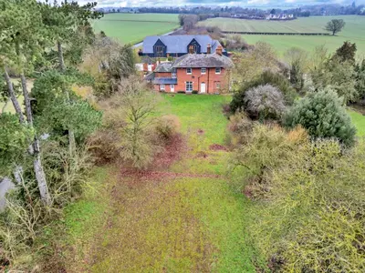 an aerial view of a house on a hill with trees at Finest Retreats - Clavering Hall in Saffron Walden