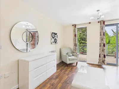 a white bathroom with a mirror and a chair at Station Apartment in Cambridge