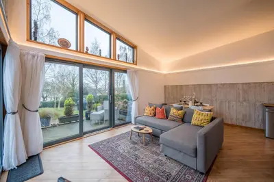 a living room with a gray couch and large windows at The Orchard Annexe, Framlingham in Framlingham