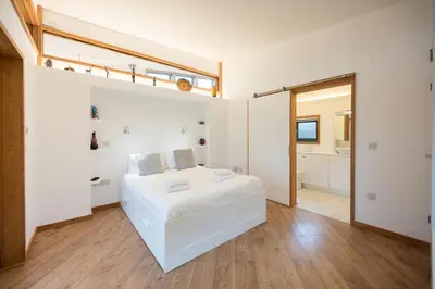 a white bedroom with a large bed and a bathroom at The Orchard Annexe, Framlingham in Framlingham
