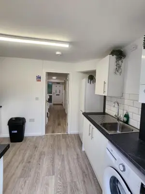 a kitchen with white cabinets and a wooden floor at Ensuite premier rooms in Basildon