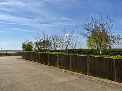a wooden fence next to a road with trees at Ivy No1 - Uk49251 in Althorne