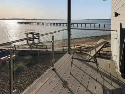 a chair sitting on a deck next to the water at Admiralty Lodge in Shotley Gate
