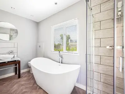 a white bathroom with a tub and a glass shower at Essex Barn House - Uk48354 in Romford
