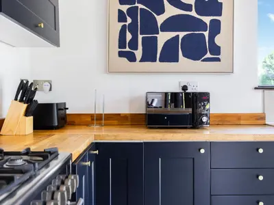 a kitchen with navy blue cabinets and a stove at Essex Barn House - Uk48354 in Romford