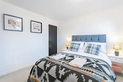 a bedroom with a large bed with white walls at A lovely modern comfortable one bedroom house - Pass the Keys in Southend-on-Sea