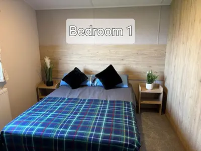 a bedroom with a bed with a plaid blanket at M&B Holiday Home and Caravan in Saint Osyth