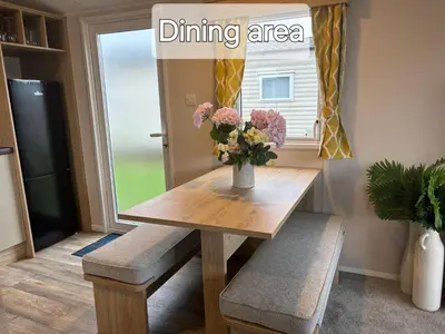 a dining room table with a vase of flowers on it at M&B Holiday Home and Caravan in Saint Osyth