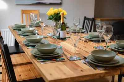 a wooden table with plates and glasses and a bottle of wine at Stunning City Home with Private Heated Indoor Pool & Cinema Room in Cambridge