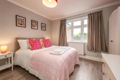 a bedroom with a bed with red pillows and a window at Stunning City Home with Private Heated Indoor Pool & Cinema Room in Cambridge