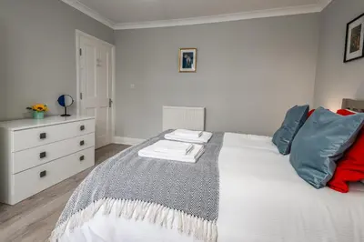 a bedroom with a white bed with blue and red pillows at Stunning City Home with Private Heated Indoor Pool & Cinema Room in Cambridge