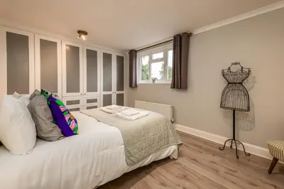 a bedroom with a bed with white sheets and a window at Stunning City Home with Private Heated Indoor Pool & Cinema Room in Cambridge