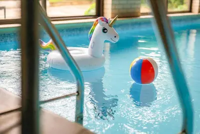a toy unicorn in a swimming pool with a ball at Stunning City Home with Private Heated Indoor Pool & Cinema Room in Cambridge