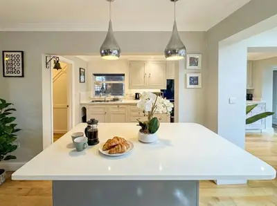 a kitchen with a white island with a plate of croissants at Stunning City Home with Private Heated Indoor Pool & Cinema Room in Cambridge