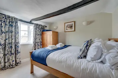 a bedroom with a bed with blue and white sheets and a window at Winter Cottage, Clare in Clare