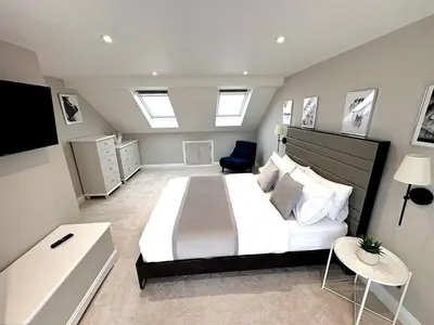 a bedroom with a large white bed and a chair at Luxury home Cheshunt in Wormley