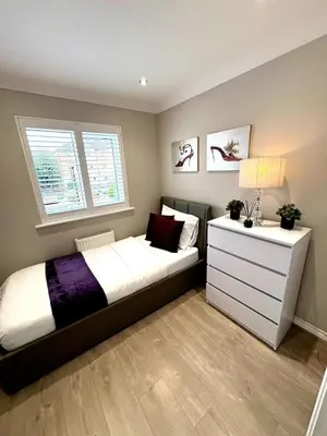 a bedroom with a bed with a dresser and a window at Luxury home Cheshunt in Wormley