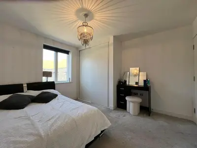 a bedroom with a large bed and a chandelier at Lovely 2 Bedroom Apartment in Trumpington