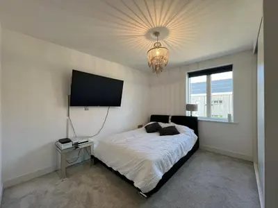 a bedroom with a bed and a television on the wall at Lovely 2 Bedroom Apartment in Trumpington