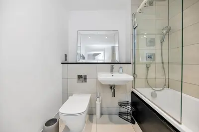 a white bathroom with a toilet and a sink at Lovely 2 Bedroom Apartment in Trumpington