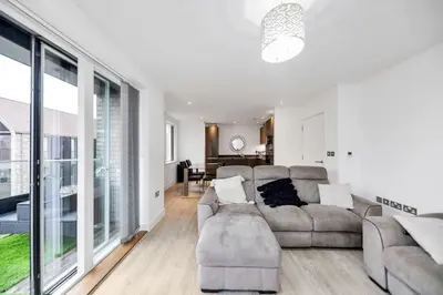 a living room with a couch and a large window at Lovely 2 Bedroom Apartment in Trumpington