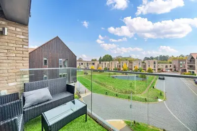 a balcony with a couch and a view of a yard at Lovely 2 Bedroom Apartment in Trumpington