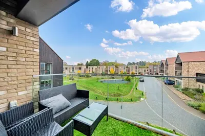 a balcony with a couch and a view of a street at Lovely 2 Bedroom Apartment in Trumpington