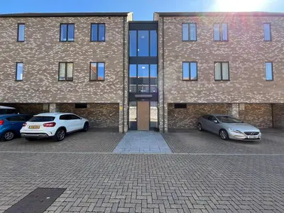 two cars parked in a parking lot in front of a building at Lovely 2 Bedroom Apartment in Trumpington