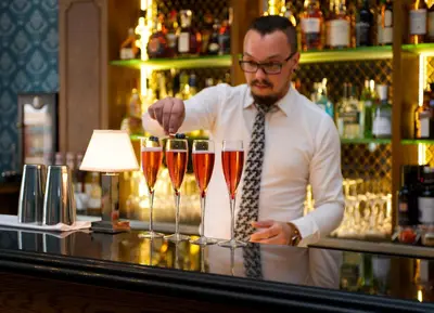 a man standing behind a bar with three wine glasses at GreyFriars in Colchester