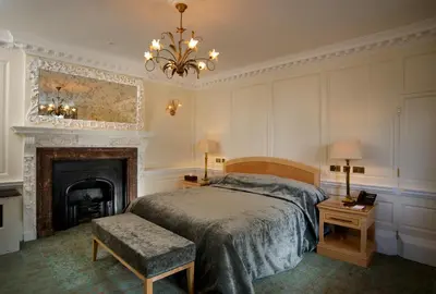 a bedroom with a bed and a fireplace and a chandelier at GreyFriars in Colchester