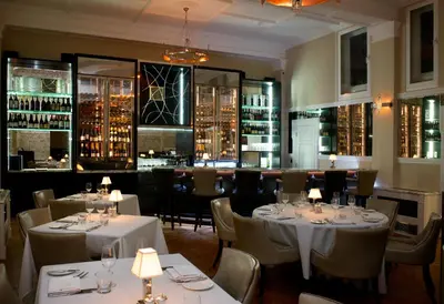 a restaurant with white tables and chairs and a bar at GreyFriars in Colchester