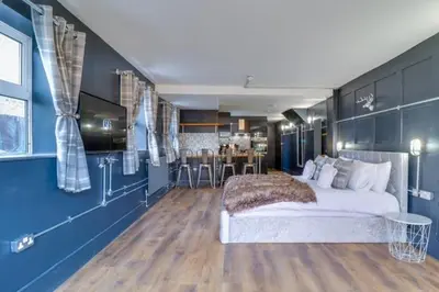 a bedroom with blue walls and a bed and a kitchen at Studio Apartment with Private Garden in Southend-on-Sea