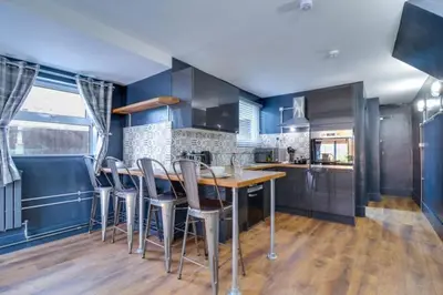 a kitchen with blue walls and a wooden table and chairs at Studio Apartment with Private Garden in Southend-on-Sea