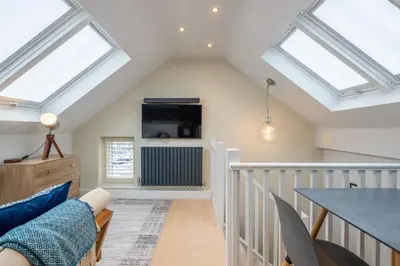 a attic living room with skylights and a table at Charming Central 1Bed Home in Chesterton