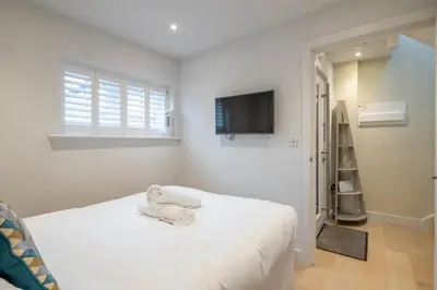 a white bedroom with a bed and a flat screen tv at Charming Central 1Bed Home in Chesterton