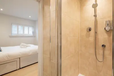 a bathroom with a walk in shower next to a bed at Charming Central 1Bed Home in Chesterton