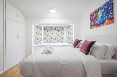 a white bed with a stuffed animal on top of it at Fabulous 4 Bed Family Home in Cherry Hinton