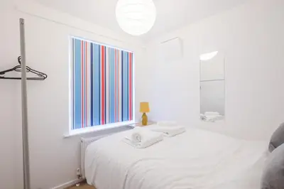 a white bedroom with a white bed and a window at Fabulous 4 Bed Family Home in Cherry Hinton
