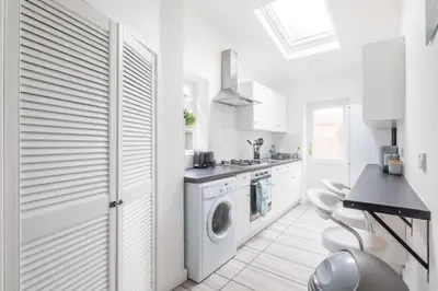 a white kitchen with a washer and dryer in it at Fabulous 4 Bed Family Home in Cherry Hinton