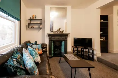 a living room with a leather couch and a fireplace at 21 Urban Road, sleeps 5 guests, Leiston, near Sizewell, Managed by Aldeburgh Coastal Cottages in Leiston