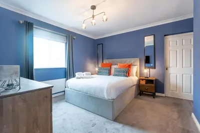 a bedroom with blue walls and a bed with orange pillows at Comfortable 3 bedroom Home Chelmsford Sleeps 5 - Pass the Keys in Chelmsford
