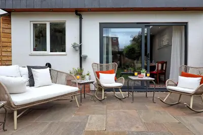 a patio with wicker chairs and tables and a door at Spacious 4-Bedroom Home Near Station Seafront - Pass the Keys in Southend-on-Sea