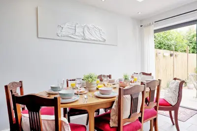 a dining room with a wooden table and chairs at Spacious 4-Bedroom Home Near Station Seafront - Pass the Keys in Southend-on-Sea