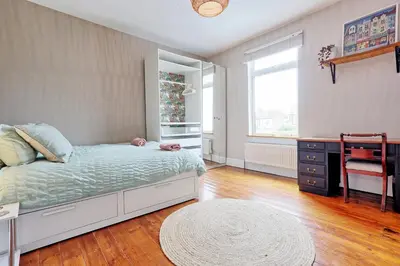 a bedroom with a bed and a desk and a window at Spacious 4-Bedroom Home Near Station Seafront - Pass the Keys in Southend-on-Sea