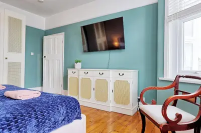 a bedroom with a bed and a tv on the wall at Spacious 4-Bedroom Home Near Station Seafront - Pass the Keys in Southend-on-Sea