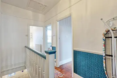 a hallway with a staircase with blue carpet at Spacious 4-Bedroom Home Near Station Seafront - Pass the Keys in Southend-on-Sea