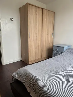 a bedroom with a bed and a wooden cabinet at House in Colchester with parking in Colchester