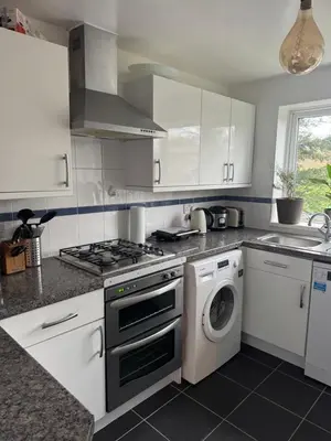a kitchen with a stove and a washing machine at House in Colchester with parking in Colchester