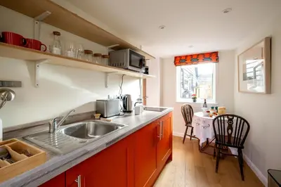 a kitchen with a sink and a table with chairs at Oak Barn - Sleeps 3, Sweffling, near #Sizewell #Aldeburgh #Saxmundham - Managed by Aldeburgh Coastal Cottages in Rendham